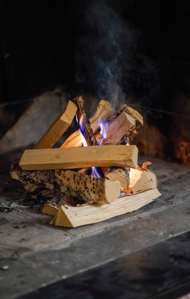 Close-up of firewood burning with blue flames in a cozy fireplace.